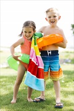 Girl (4-5) and boy (6-7) holding towel and inflatable rings