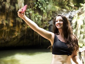 Caribbean Islands, Saint Lucia, woman taking selfie by waterfall