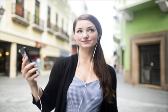 Puerto Rico, San Juan, woman with smartphone and earphones on street