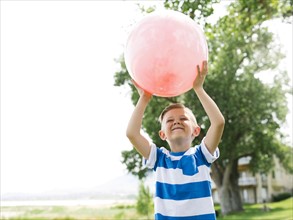 USA, Utah, Salt Lake City, Boy (6-7) playing with large pink ball