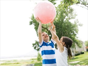 USA, Utah, Salt Lake City, Boy (6-7) and girl (4-5) playing with large pink ball