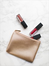 Lip glosses and purse on marble background