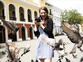 Puerto Rico, San Juan, Woman standing on street and photographing pigeons