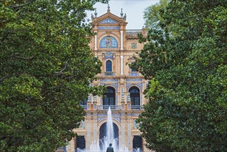 Spain, Seville, Plaza De Espana, Fountain among trees, building in background
