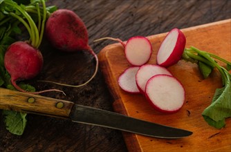Slices of red radish and knife on cutting board