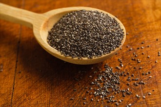 Wooden spoon full of chia seeds on table