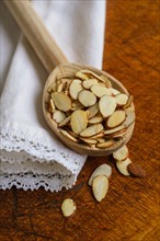 Wooden spoon full of sliced almond on table