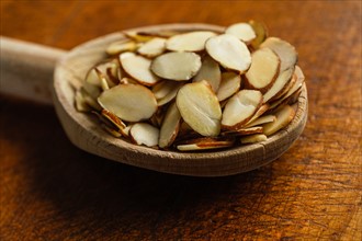 Wooden spoon full of sliced almonds on table