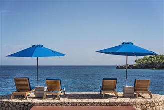 Jamaica, Negril, Beach umbrellas and lounge chairs against tranquil seascape