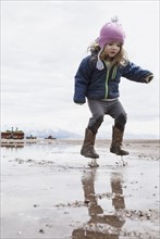 Little girl (4-5) jumping in puddle