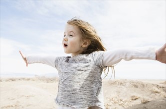 Portrait of little girl (4-5) with outstretched arms and open mouth in field