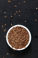 Bowl full of flax seeds on black background