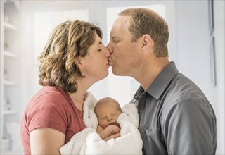 Parents holding and baby son (0-1 months) and kissing each other