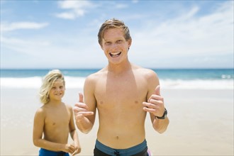 Young man with younger brother (4-5) playing at beach