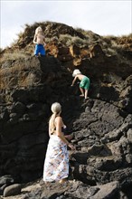 USA, Hawaii, Kauai, Mother with sons (4-5, 8-9) climbing on rocks