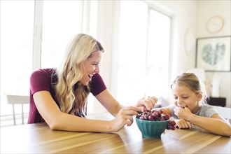 Mother and daughter (6-7) eating grapes