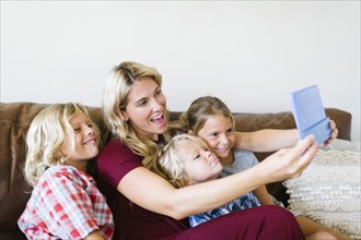 Mother and children (4-5, 6-7, 8-9) taking selfie with digital tablet
