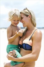 Mother with son (4-5) embracing at beach