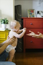Parents assisting in son's (12-17 months) first step
