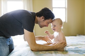 Father playing with baby boy (12-17 months) in bedroom