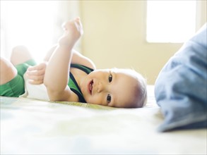 Portrait of baby boy (12-17 months) lying on bed and looking at camera