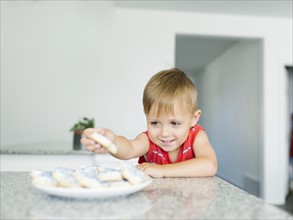 Boy (2-3) reaching for cookies on kitchen counter