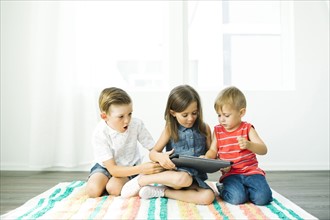 Siblings (2-3, 6-7) using digital tablet at home
