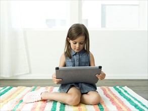 Girl (6-7) using digital tablet at home