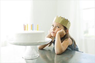 Sad girl (6-7) with birthday cake