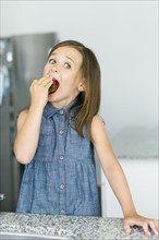 Portrait of girl (6-7) eating strawberry