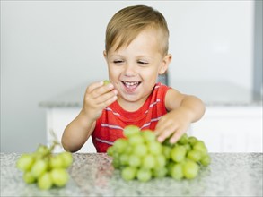 Boy (2-3) eating white grapes