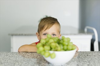 Boy (2-3) hiding behind bowl with grapes