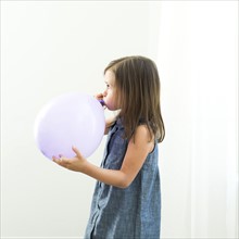 Girl (6-7) blowing balloon