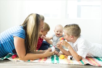 Mother playing with her three children (6-11 months, 2-3, 6-7)