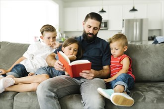 Father with his three children (2-3, 6-7) reading book
