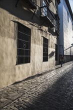 Spain, Andalusia, Granada, Woman walking along cobblestone street