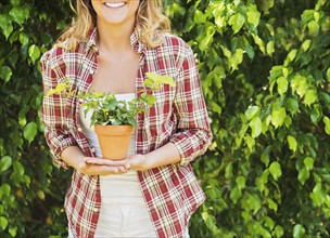 Smiling woman holding potted plant