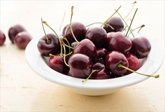 Ripe cherries in white bowl on table