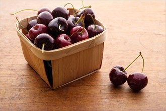 Basket full of cherries on wooden table