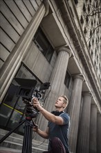 Camera operator filming in front of building