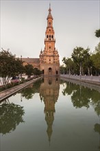 Spain, Andalusia, Seville, Plaza de Espana, Tower reflecting in water surface