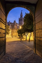 Spain, Andalusia, Seville, Arched corridor with Seville Cathedral (Cathedral of Saint Mary of the See) in background