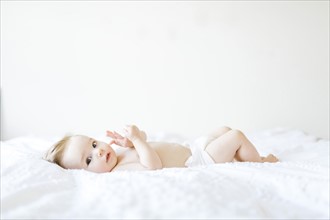Portrait of baby girl (6-11 Months) lying down on bed