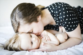 Baby girl (6-11 Months) being hugged by mother