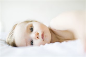 Portrait of baby girl (6-11 months) lying on bed