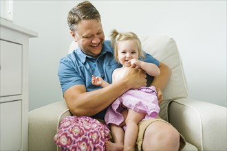 Father with baby girl (12-17 months) sitting in living room
