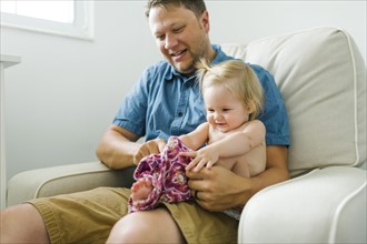 Father with baby girl (12-17 months) sitting in living room