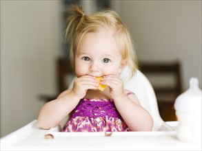 Portrait of baby girl (12-17 months) eating lunch