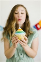 Mid adult woman blowing birthday candle