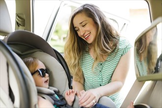 Mother preparing baby girl (12-17 months) for car trip